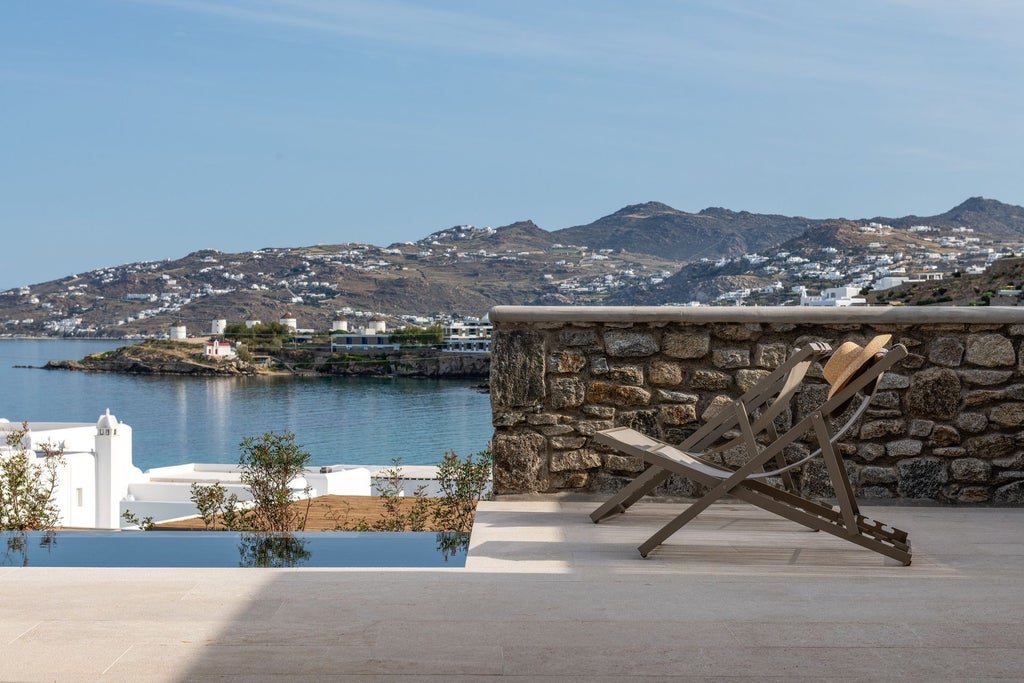 Luxurious white-washed Scenset hotel overlooking azure Aegean waters, with minimalist Cycladic architecture and elegant infinity pool at sunset