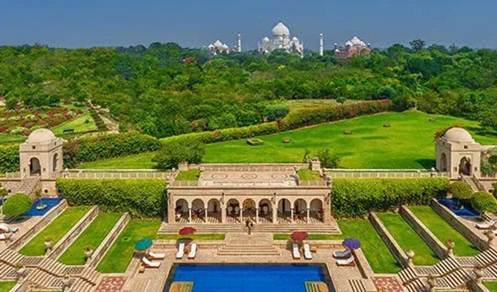 Elegant marble facade of Oberoi Amarvilas hotel with ornate Mughal architecture, reflecting pools, and manicured gardens at twilight