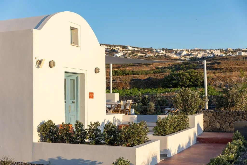 Luxurious white-washed Greek hotel with blue-domed roofs overlooking the stunning azure Aegean Sea in picturesque Scenset landscape