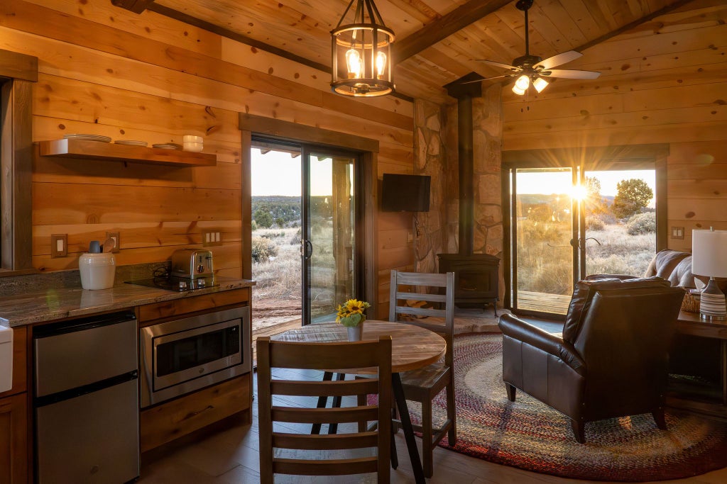 Rustic lodge room with wooden furnishings, plush king bed, large windows overlooking scenic mountain landscape at Scenset Mountain Ranch, United States