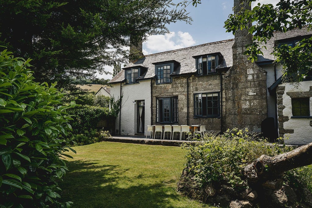 Historic stone farmhouse in scenic UK countryside, with rustic stone walls, elegant landscaped gardens, and traditional architectural details showcasing rural luxury and timeless charm