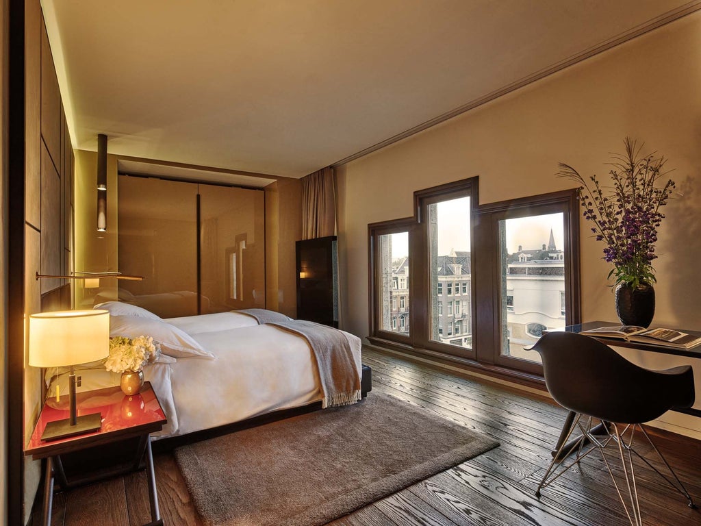 Luxurious Conservatorium Suite with elegant modern decor, soft neutral tones, spacious layout, floor-to-ceiling windows overlooking Amsterdam's historic cityscape