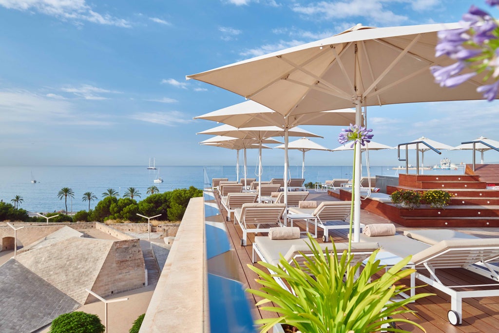 Five-star hotel Es Princep features a modern white facade with glass balconies, overlooking Palma Bay and Mediterranean Sea at golden hour