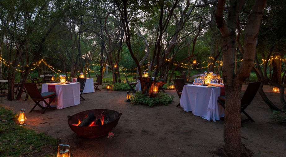 Luxurious safari lodge with thatched roof overlooking private deck and infinity pool against vast African savanna backdrop