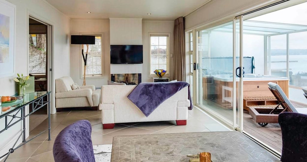 Luxurious lake-view cottage bedroom with panoramic scenery, modern minimalist design, crisp white linens, and expansive windows overlooking New Zealand's pristine landscape