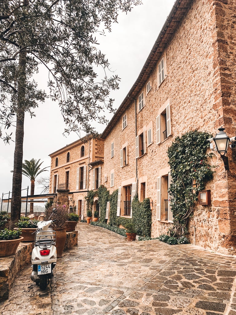 Elegant Mediterranean hotel nestled in Mallorca's Tramuntana mountains, featuring stone architecture and lush terraced gardens