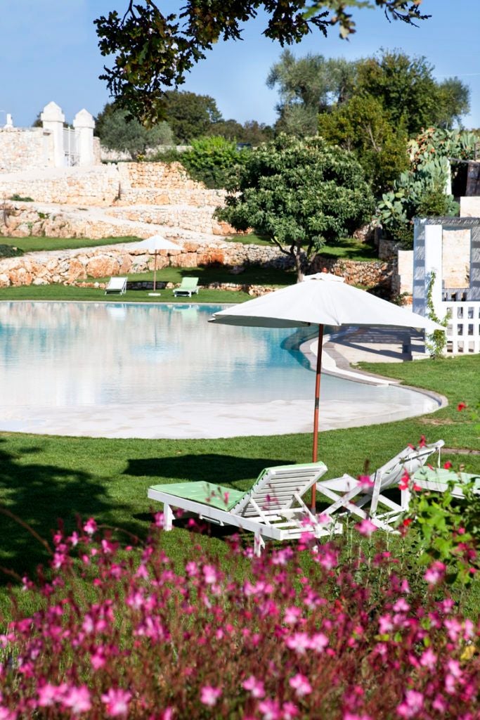 Rustic stone Italian farmhouse with elegant white-washed walls, surrounded by lush olive groves and lavender fields in scenic Puglia countryside.