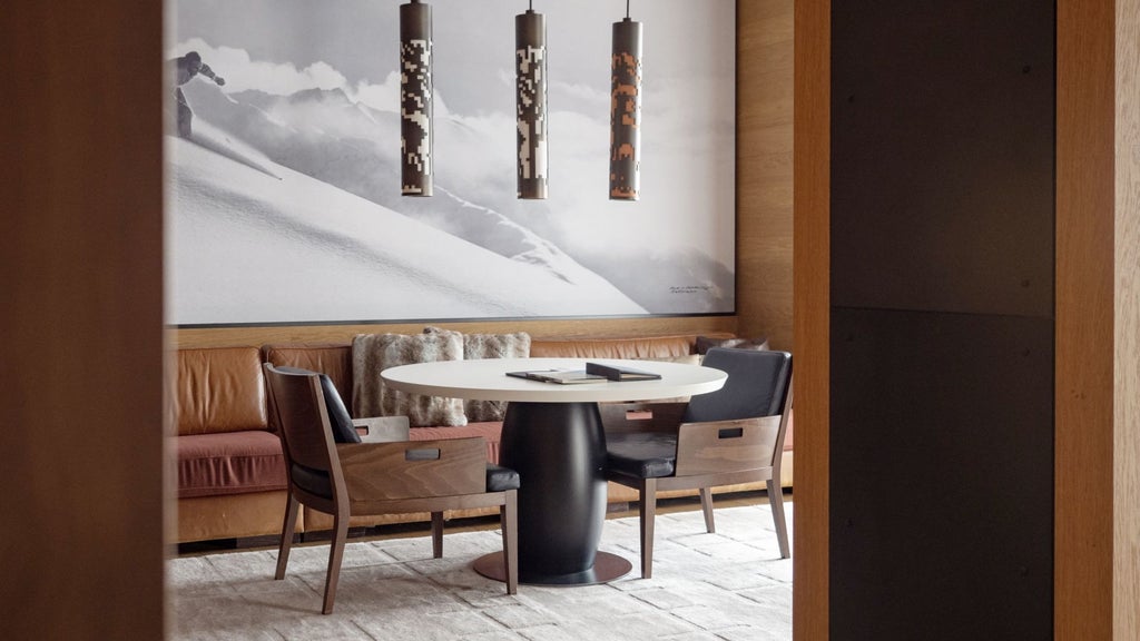 Minimalist alpine-inspired luxury suite with wooden floors, floor-to-ceiling windows, elegant furniture, and panoramic mountain views of Swiss Alps landscape