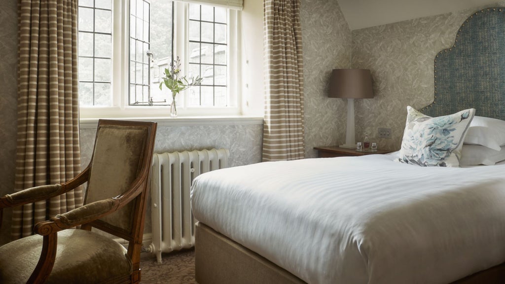 Elegant single room at Bovey Castle Hotel, featuring classic British decor, plush furnishings, and expansive countryside views through large windows.