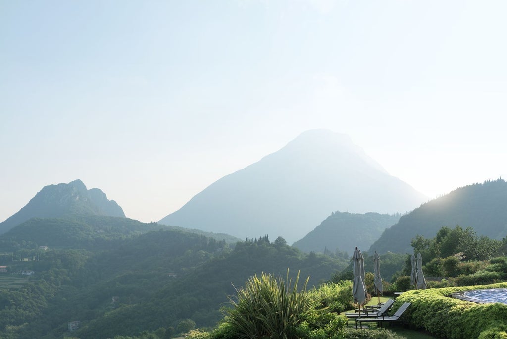 Luxurious mountain resort overlooking Lake Garda with infinity pool, stone terraces and panoramic views of Italian countryside at sunset