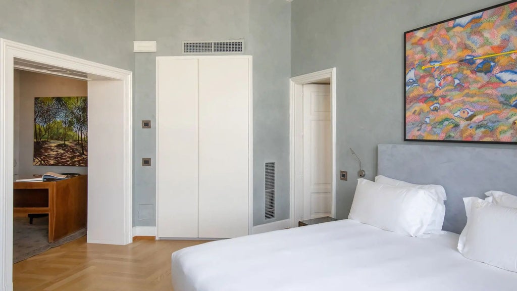 Luxurious master suite with modern Italian design, featuring plush white bedding, sleek furnishings, and large windows overlooking urban Milan landscape