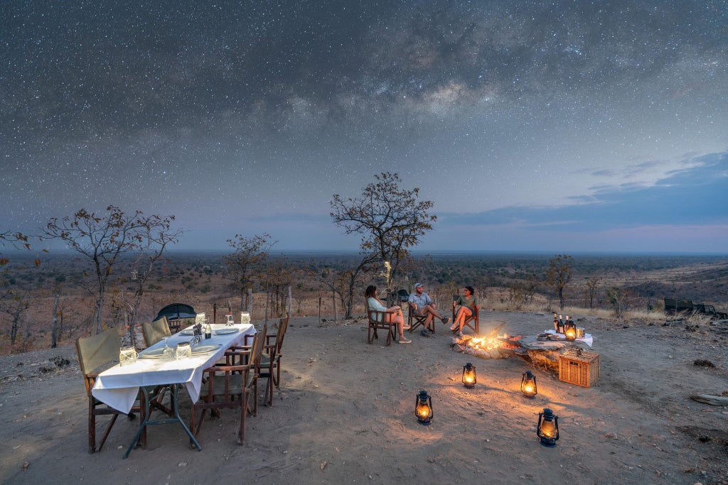 Luxury safari tented suite overlooking lush Lower Zambezi riverbank with wooden deck, canvas walls, and panoramic wilderness views of Zambian landscape