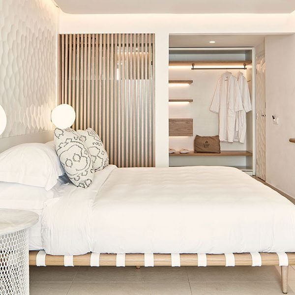 Luxurious white-washed Cycladic suite with private balcony overlooking deep blue Aegean Sea, minimalist design with elegant curves at Myconian resort