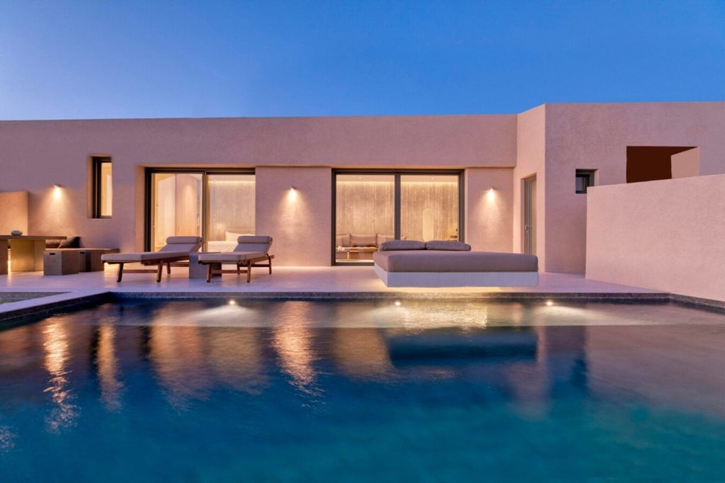 Luxurious white-washed Santorini villa perched on cliff edge, overlooking deep blue Aegean Sea with stunning infinity pool at sunset