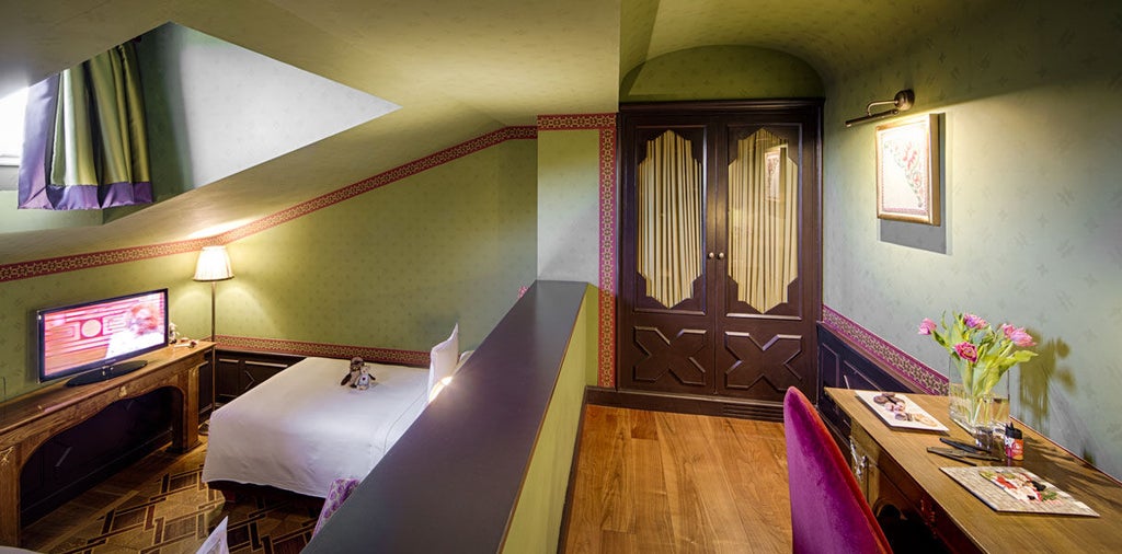 Elegant villa hotel room with ornate gold-framed mirror, antique furniture, Murano glass chandelier, and traditional Italian decor