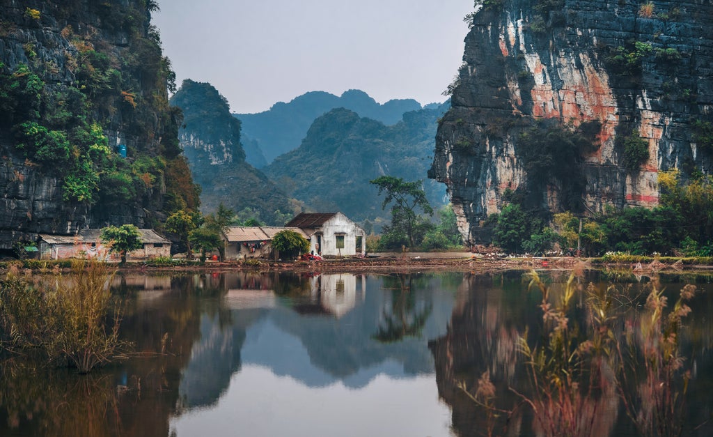 Cyclists explore scenic countryside paths alongside Red River, passing traditional villages and lush rice fields near Hanoi at sunset