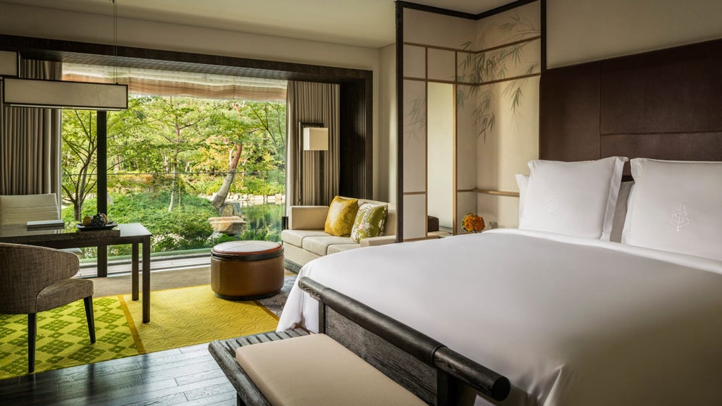 Alt text: Elegant Japanese hotel room with floor-to-ceiling windows overlooking zen garden, featuring sleek wooden furnishings and soft natural light