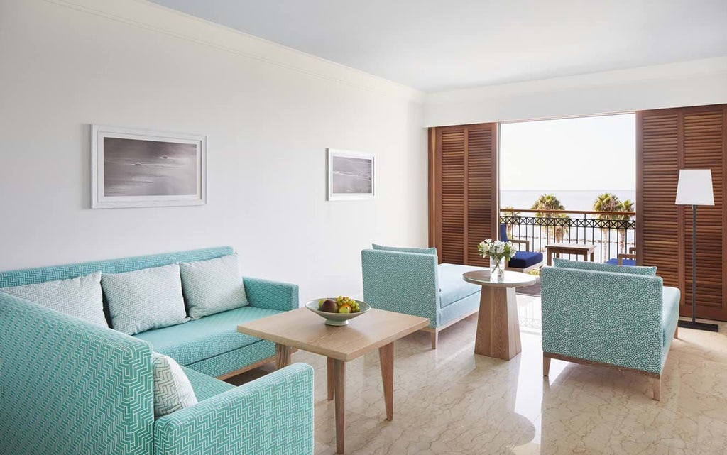 Luxurious Karyatis Sea View Suite at scenic Cypriot hotel, featuring elegant maritime-inspired decor, plush white bedding, and expansive blue sea panorama