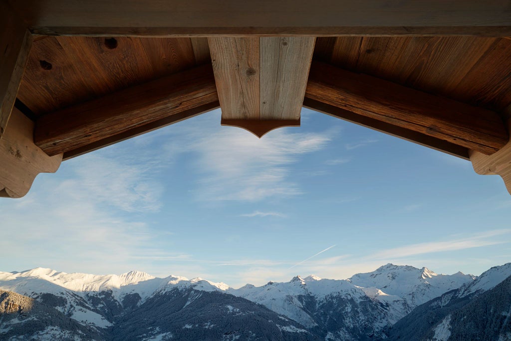 Luxurious alpine chalet with modern glass walls, set against snow-covered peaks at Six Senses Residences Courchevel, showcasing elegant mountain retreat design