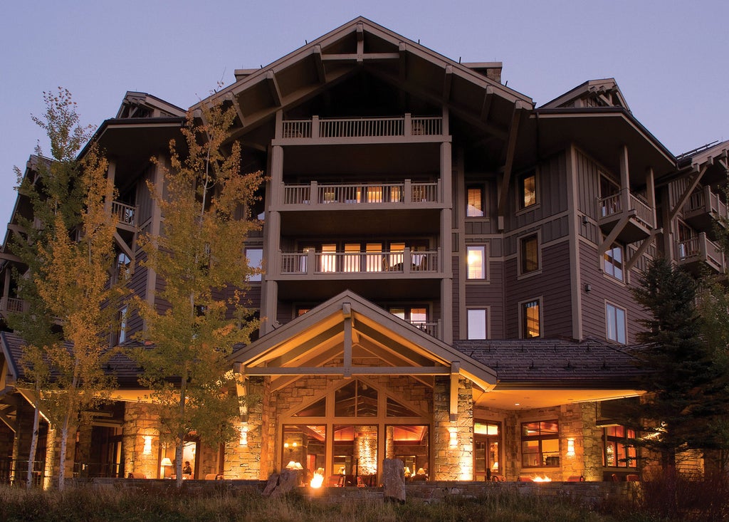 Luxury mountain resort Four Seasons Jackson Hole with snow-capped peaks, stone facade, grand entrance and multiple balconies overlooking slopes