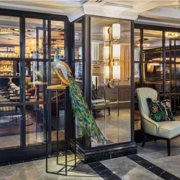 Elegant Mayfair Townhouse hotel facade with gleaming white exterior, ornate black ironwork, and classic London architectural charm at dusk