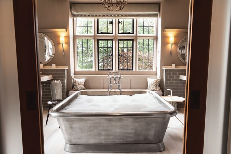 Luxurious chestnut-toned hotel room at Foxhill Manor with elegant furnishings, soft lighting, and plush bedding overlooking picturesque countryside views