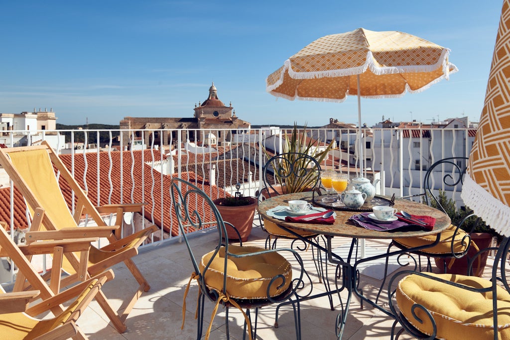 Elegant boutique hotel in Spain with whitewashed Mediterranean facade, featuring ornate balconies and traditional wooden shutters