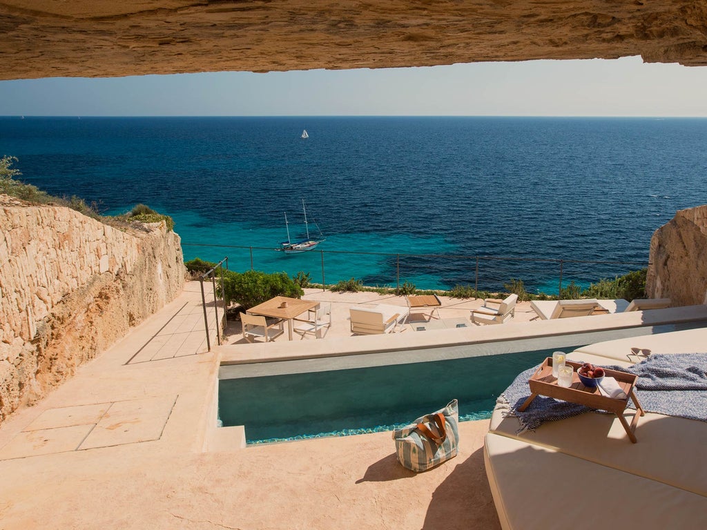 Luxury Spanish fortress hotel Cap Rocat features stone archways and terraces overlooking Mediterranean Sea at golden sunset hour