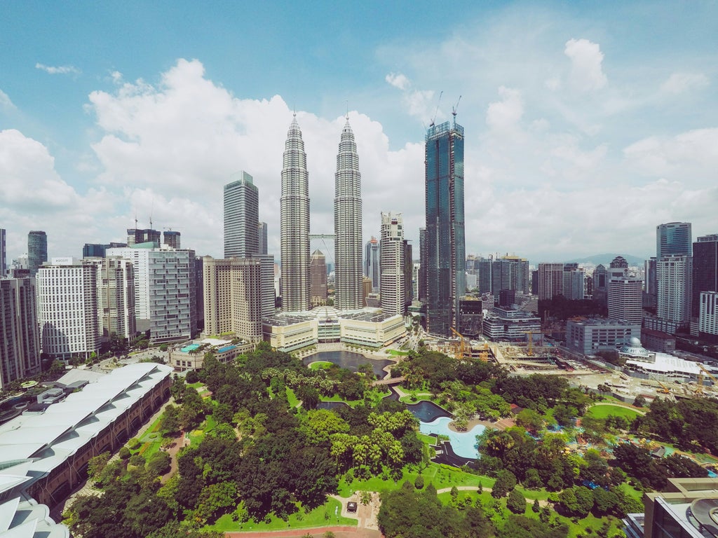 Modern skyline of Kuala Lumpur with iconic Petronas Twin Towers, lush tropical greenery, and sleek city architecture showcasing Malaysia's vibrant urban landscape