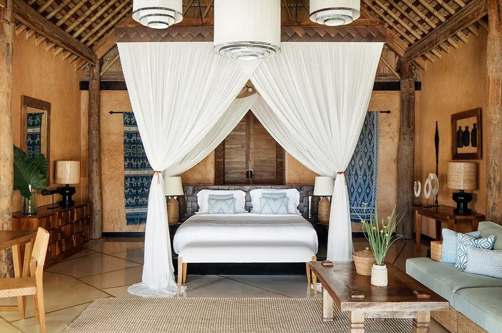 Luxurious open-air suite at NIHI Sumba Lantoro Estate, overlooking lush tropical landscape with private infinity pool and rustic-chic wooden design