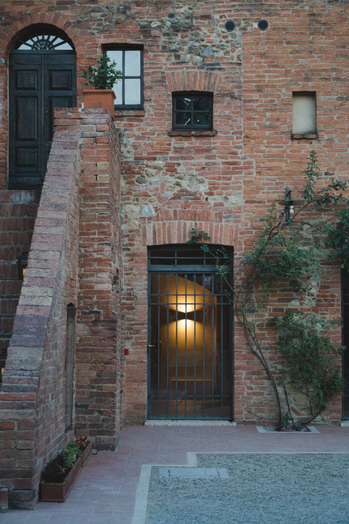 Elegant Tuscan boutique hotel with stone facade, arched windows and romantic balconies adorned with potted plants and climbing vines