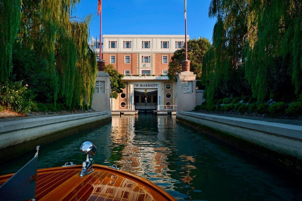 Elegant Venetian luxury hotel with private island setting, featuring grand marble entrance, manicured gardens and waterfront views