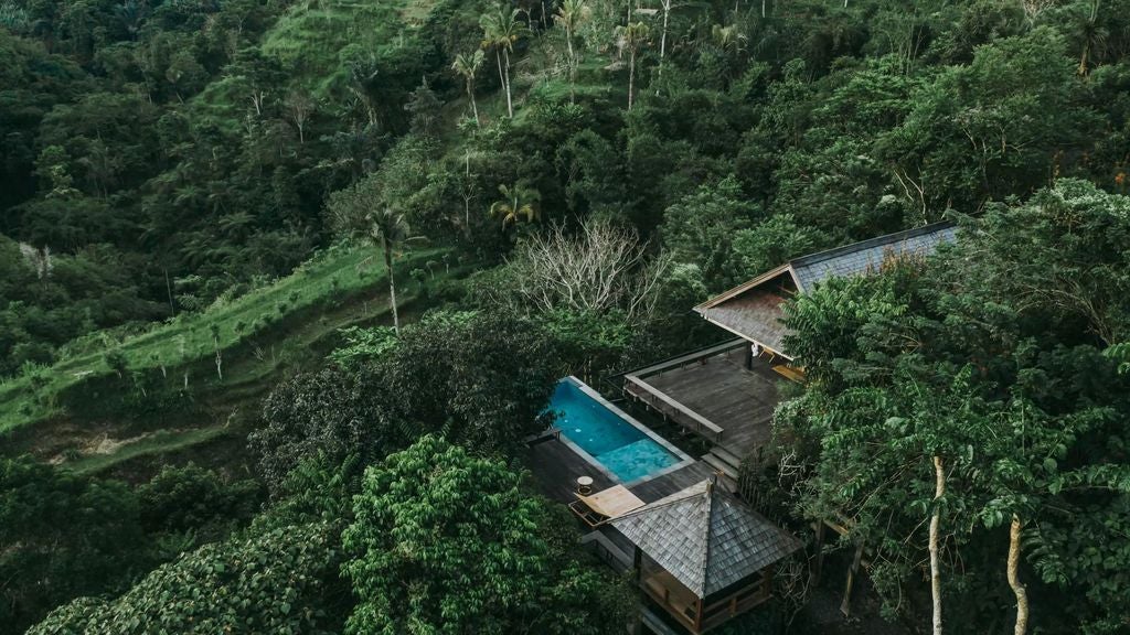 Luxurious open-air villa in Bali rainforest featuring infinity pool, traditional wooden architecture and panoramic jungle views