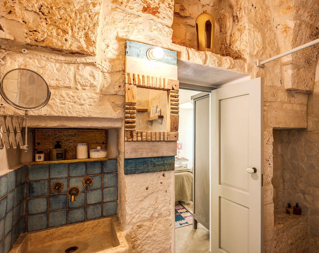 Rustic stone walls meet elegant furnishings in this classic Italian masseria bedroom with warm neutral tones and traditional architectural details