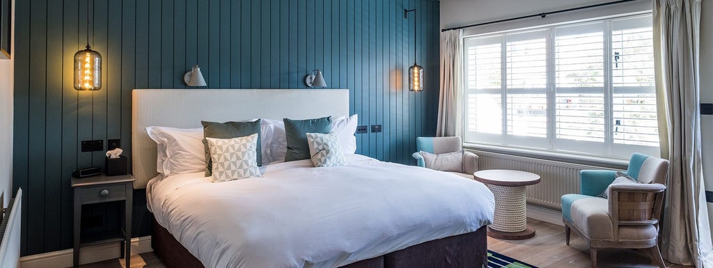 Elegant coastal hotel room at The Swan Southwold with plush white bed, nautical-inspired decor, and soft natural lighting overlooking seaside landscape