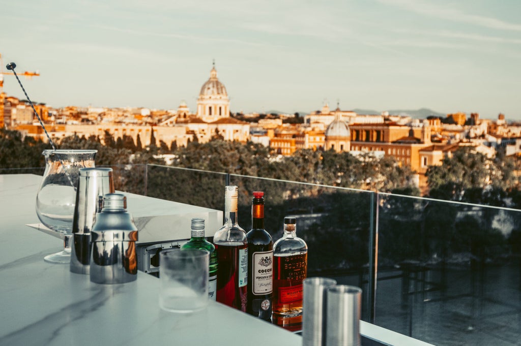 Elegant rooftop terrace of The First Roma Musica hotel with plush lounge seating, panoramic Roman city views and modern glass railings