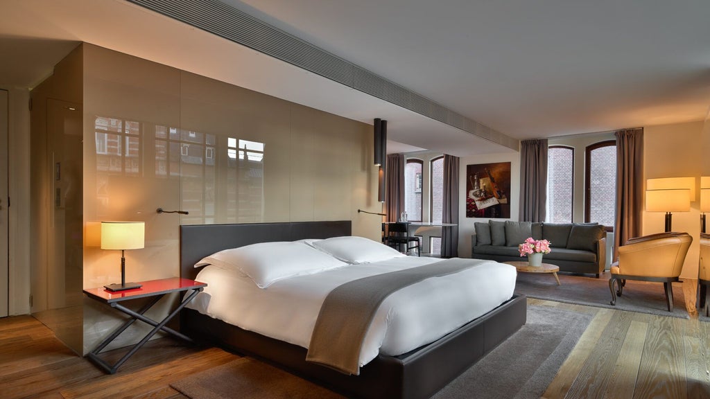 Luxurious grand junior suite with modern design, high ceilings, expansive windows, elegant furnishings, and soft neutral color palette in Amsterdam's iconic Conservatorium Hotel