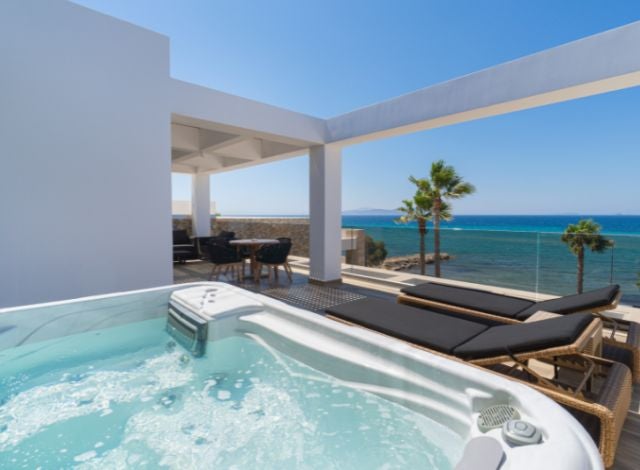 Luxurious penthouse suite with panoramic sea views, modern design, private jacuzzi, and elegant white interiors at a Greek coastal spa hotel