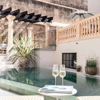 Elegant boutique hotel in Palma de Mallorca with white facade, minimalist design, and lush tropical plants framing luxurious Mediterranean architectural style