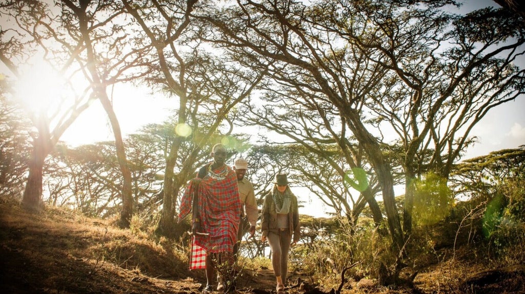 Luxury safari tent overlooking vast Tanzanian plains, with golden sunrise illuminating dramatic Ngorongoro Crater landscape and elegant outdoor seating area