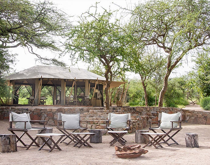 Luxurious safari tent at Mila Camp overlooking Tanzanian savanna, with private deck, canvas walls and modern furnishings at sunset