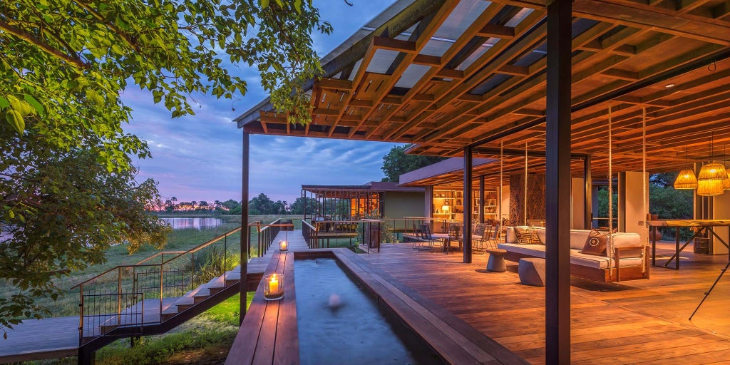 Elevated luxury lodge overlooking African delta with wooden deck, infinity pool, and contemporary thatched-roof architecture