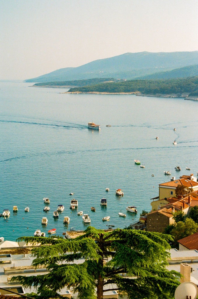 Aerial view of a charming Croatian coastal town in Istria, with terracotta rooftops and narrow streets leading to a turquoise Adriatic Sea