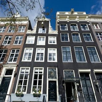 Boutique Canal House hotel in Amsterdam, featuring elegant Dutch architecture with large windows, warm lighting, and classic canal-side exterior at dusk