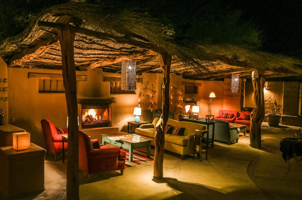 Adobe-style desert lodge with thatched roofs, outdoor terraces, and private plunge pools nestled against dramatic Atacama mountain backdrop