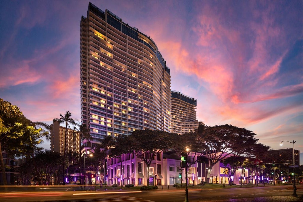 Luxurious oceanfront high-rise hotel with glass facade, infinity pool, and tropical landscaping overlooking Waikiki Beach and Pacific Ocean