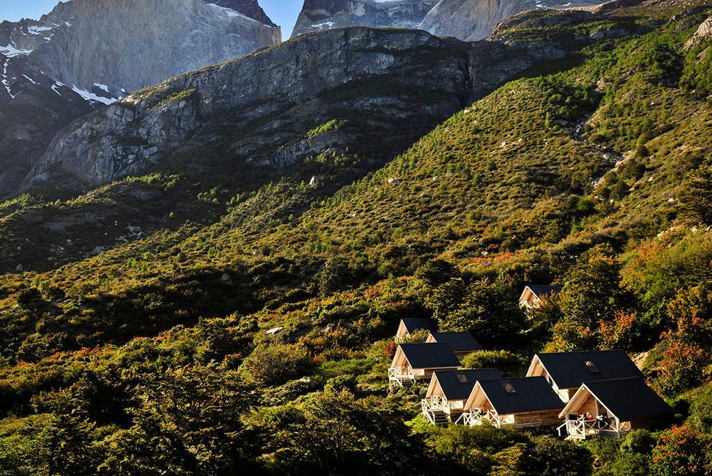 Upscale mountain lodge hotel nestled in Torres del Paine National Park, featuring rustic wood architecture and dramatic Patagonian peaks