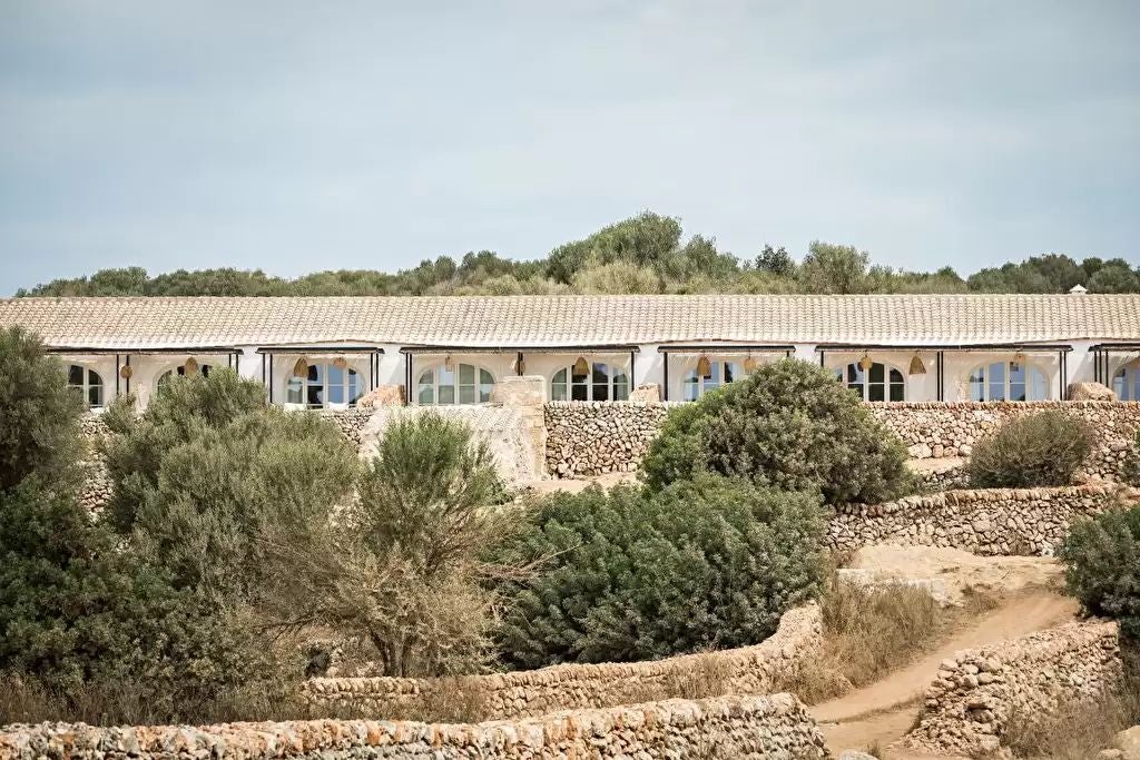 Historic Spanish coastal stone tower hotel with panoramic Mediterranean views, elegant terracotta rooftops, and lush green Mediterranean landscape