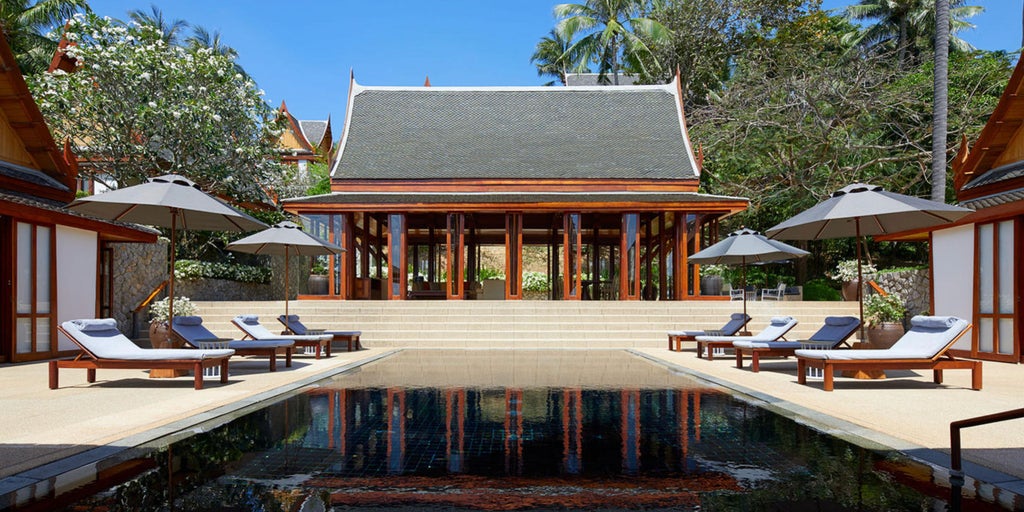 Luxurious Thai villa bedroom with ocean view, king bed, wooden accents, floor-to-ceiling windows, and private terrace with loungers