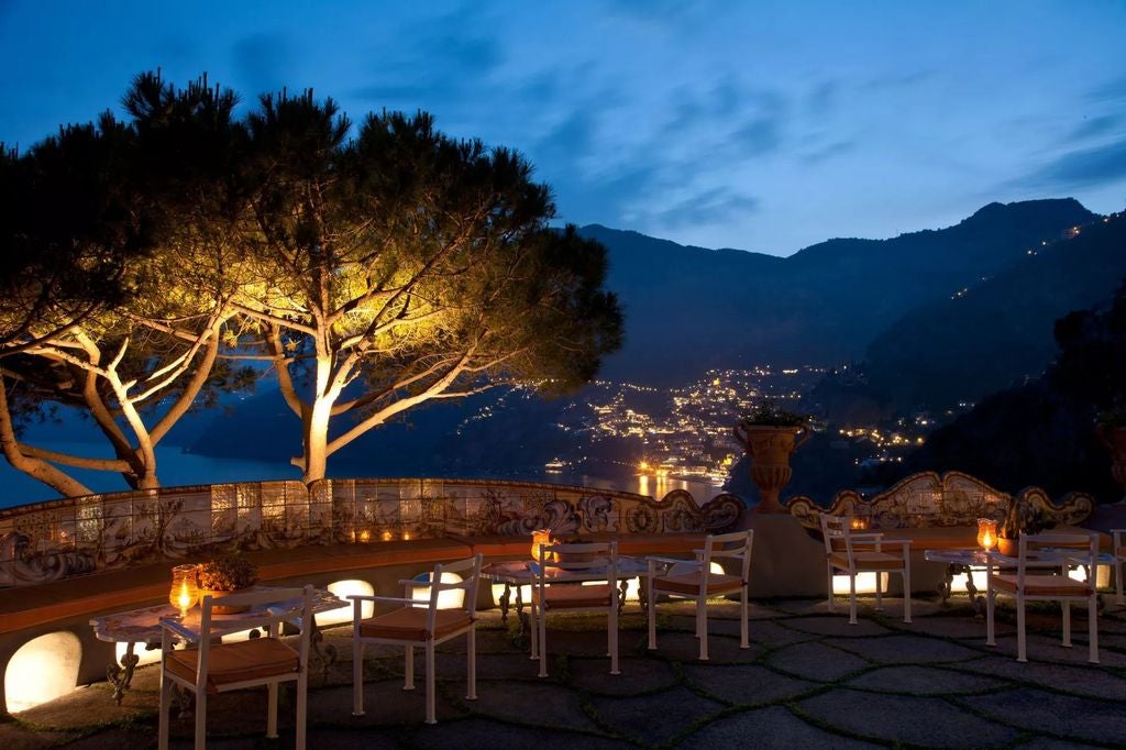 Elegant cliffside hotel in Positano featuring terraced gardens, infinity pool overlooking Amalfi Coast's azure waters and distant mountains